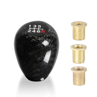Black carbon fiber gear shift knob with three brass adapters laid out.